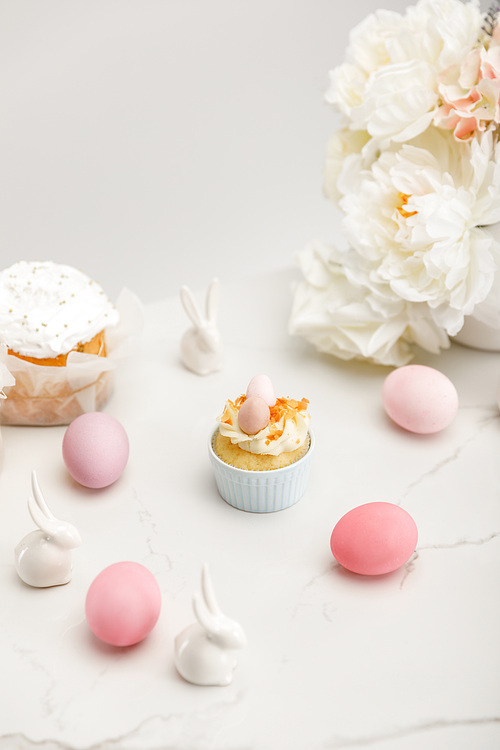 Cupcake with colorful chicken eggs, decorative bunnies, easter cakes and flowers on white background