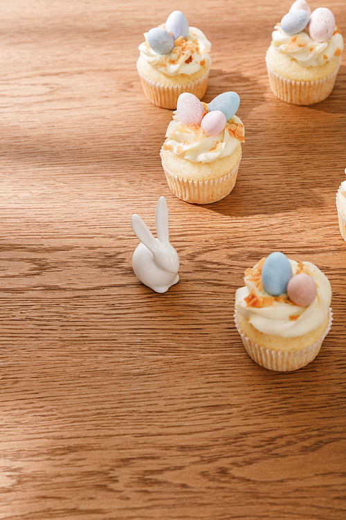 Cupcakes with decorative bunny on wooden background