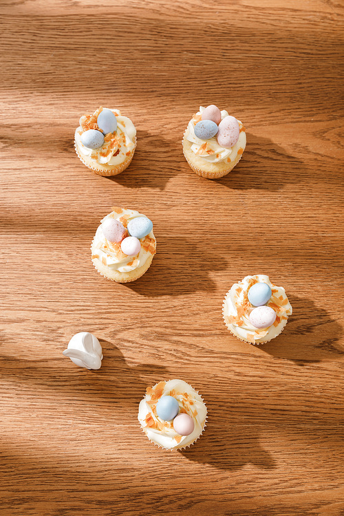 Top view of delicious cupcakes with decorative bunny on wooden background
