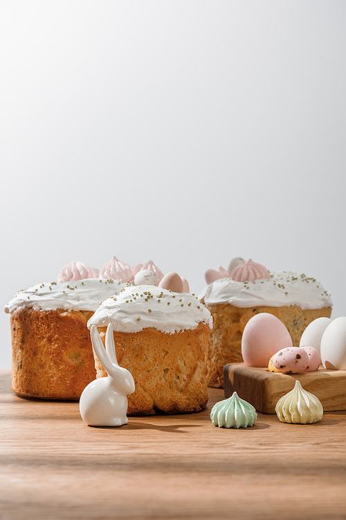 Decorative bunny, chicken and quail eggs on egg tray, meringues near Easter cakes isolated on grey
