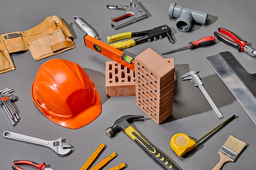 high angle view of industrial tools, bricks and helmet on grey background