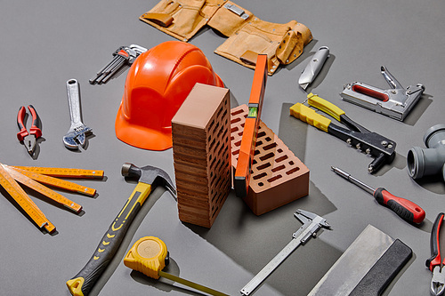 high angle view of helmet, bricks and industrial tools on grey background