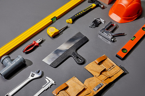 flat lay with helmet, tool belt, and industrial tools on grey background