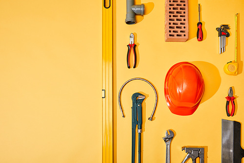 flat lay with industrial tools, measuring tape and helmet, on yellow background