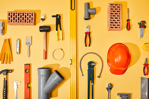 flat lay with industrial tools, bricks and helmet on yellow background