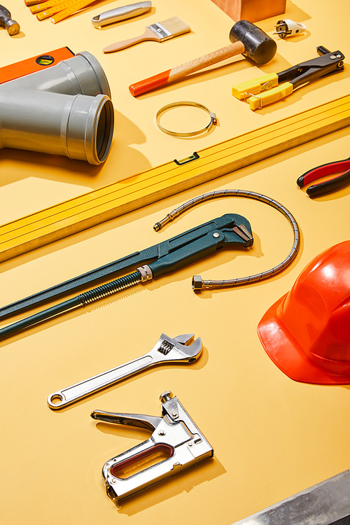 high angle view of industrial tools, plumbing hose, helmet and brush on yellow background