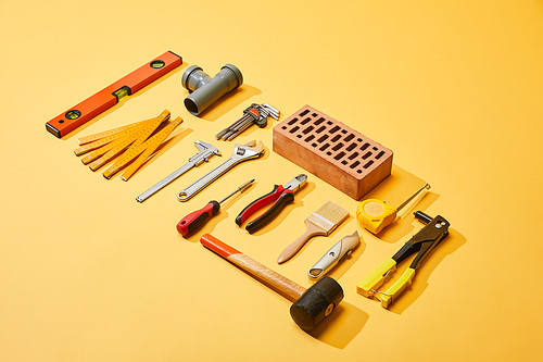 high angle view of industrial tools and brick on yellow background