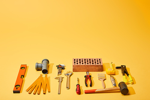 flat lay with industrial tools and brick on yellow background