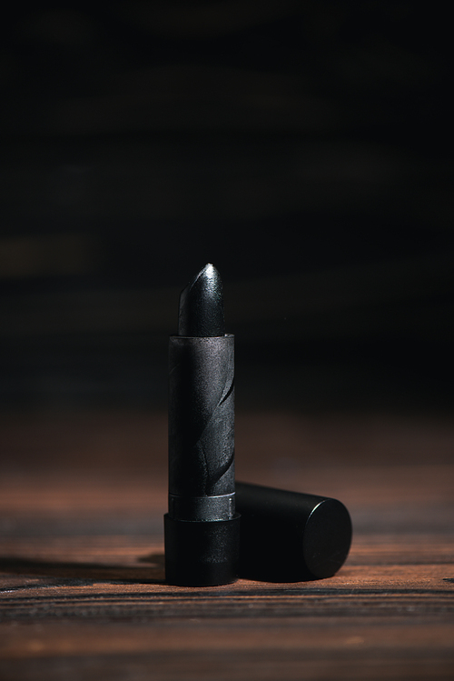 selective focus of black lipstick on wooden surface