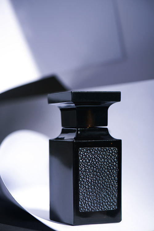 selective focus of black bottle with luxury perfume on white