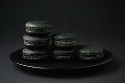 plate with dark and tasty macarons on black