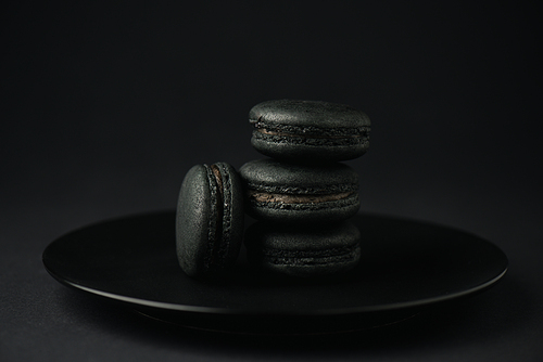 plate with dark macarons on black with copy space