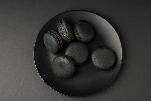 top view of plate with dark macarons isolated on black