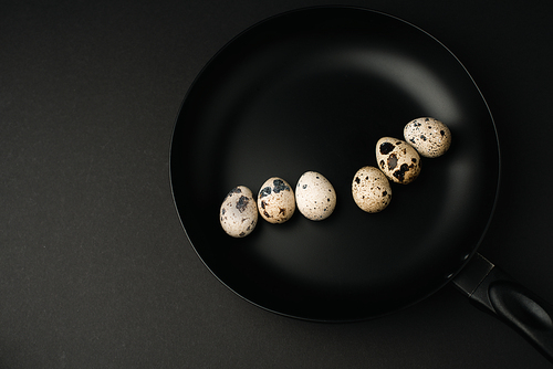 top view of quail eggs on frying pan isolated on black