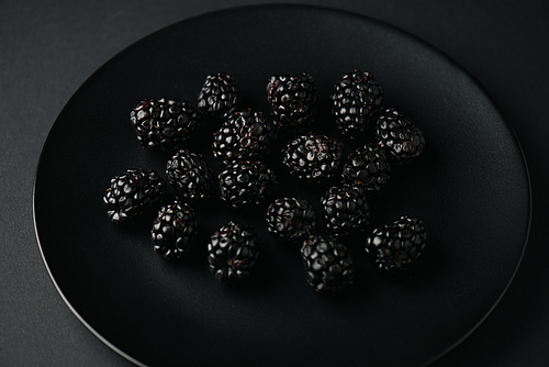 top view of plate with organic and tasty blackberries on black