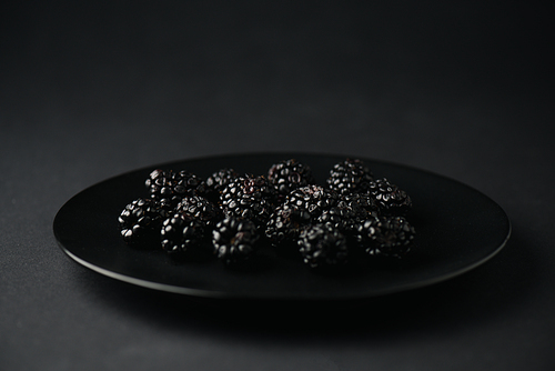 plate with organic and tasty blackberries on black