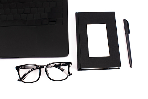 top view of laptop, notebook, pen, blank card and glasses isolated on white