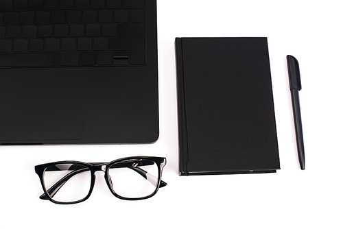 top view of laptop, notebook, pen and glasses isolated on white