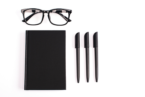 flat lay with pens near glasses and black notebook isolated on white