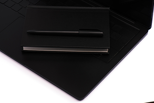 black notebook and pen on laptop keyboard isolated on white