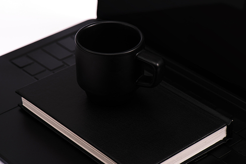black notebook and cup on laptop keyboard isolated on white
