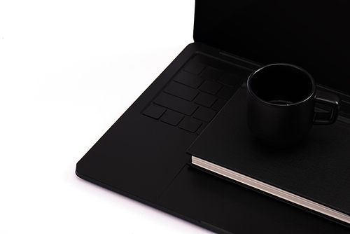 notebook and cup on black laptop isolated on white