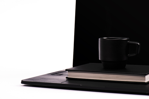 black notebook and cup on laptop with blank screen isolated on white
