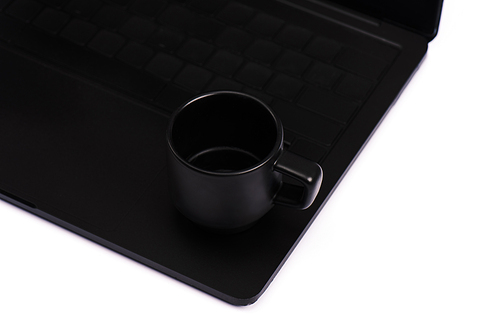 cup with drink on black laptop keyboard isolated on white