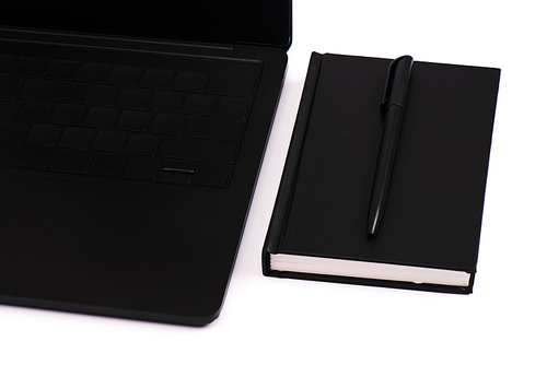 notebook and pen near black laptop isolated on white