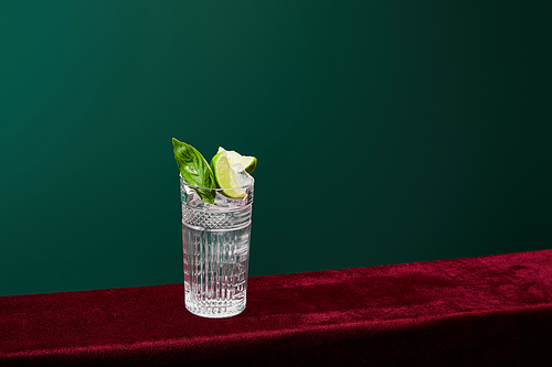 High angle view of mojito with ice, mint and lime in collins glass isolated on green