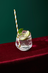 high angle view of old fashioned glass with golden rim with mojito and striped  straw isolated on green