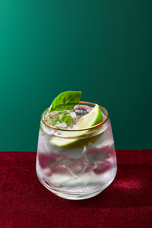 Close up view of old fashioned glass with golden rim with mojito isolated on green