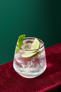high angle view of refreshing mojito with mint and ice in glass with golden rim isolated on green