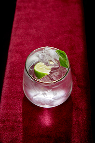 High angle view of glass with fresh cold mojito, mint and lime slice isolated on black