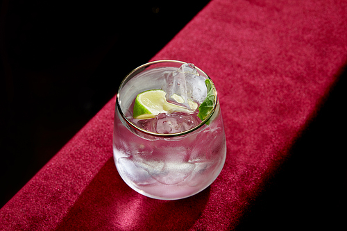 High angle view of mojito with lime, mint and ice cubes in old fashioned glass isolated on black