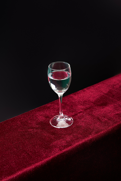 High angle view of shot glass with pure transparent liquid isolated on black