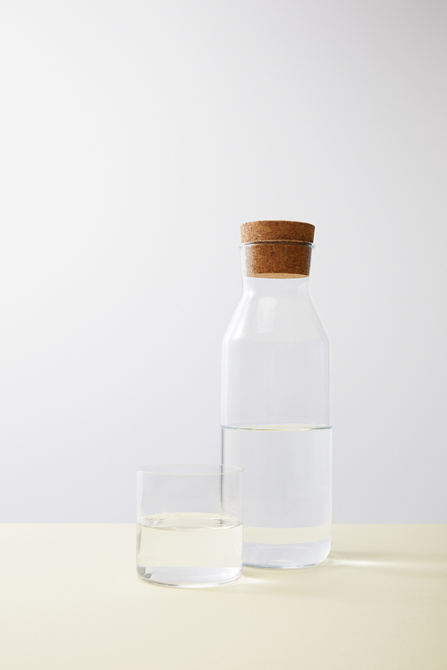 Bottle with cork and glass filled with water on isolated on grey