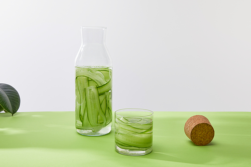 Cork, bottle and glass with drink made of sliced cucumbers isolated on grey