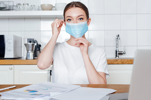 selective focus of young woman touching medical mask