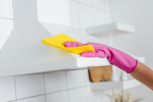 cropped view of woman in pink rubber glove cleaning kitchen hood