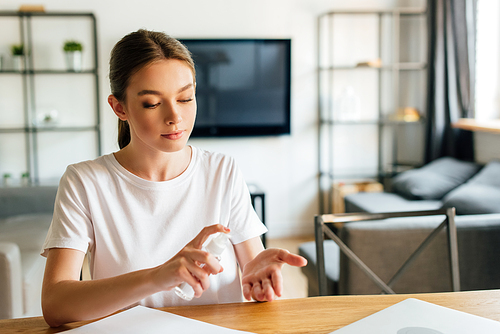 attractive woman using hand sanitizer at home