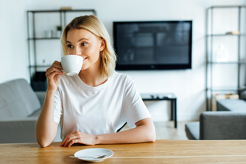 cheerful and attractive woman drinking coffee at home