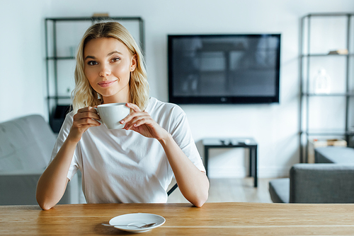 cheerful young woman  and holding cup of coffee