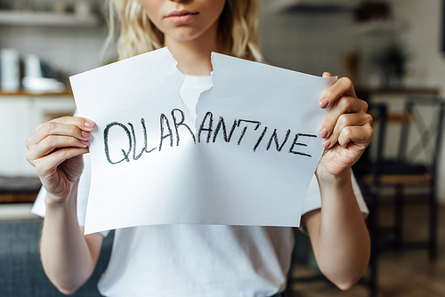 Cropped view of young woman tearing card with quarantine lettering at home