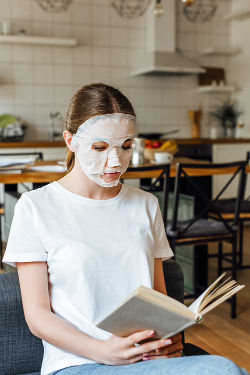 Selective focus of girl in face mask reading book on couch at home