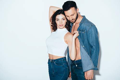 stylish couple in jeans standing together on grey