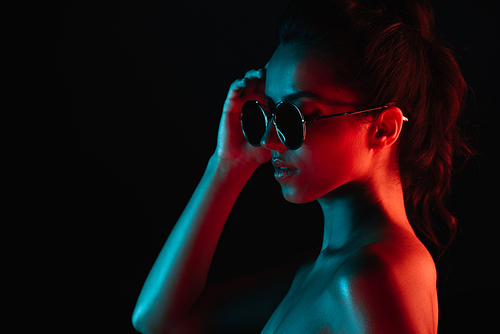 attractive young woman in sunglasses isolated on black