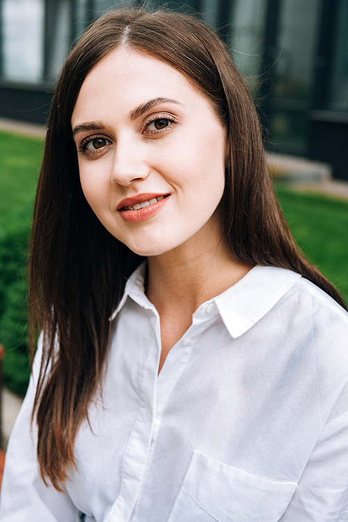 attractive smiling young woman in white shirt on street