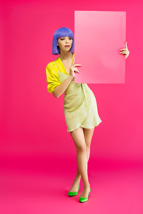 pop art girl in purple wig and yellow dress holding blank placard, isolated on pink