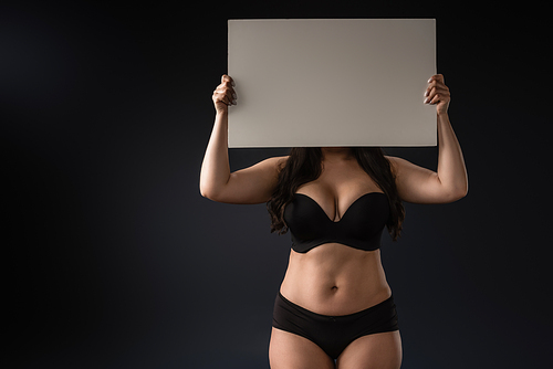 Front view of plus size model demonstrating empty board on black background